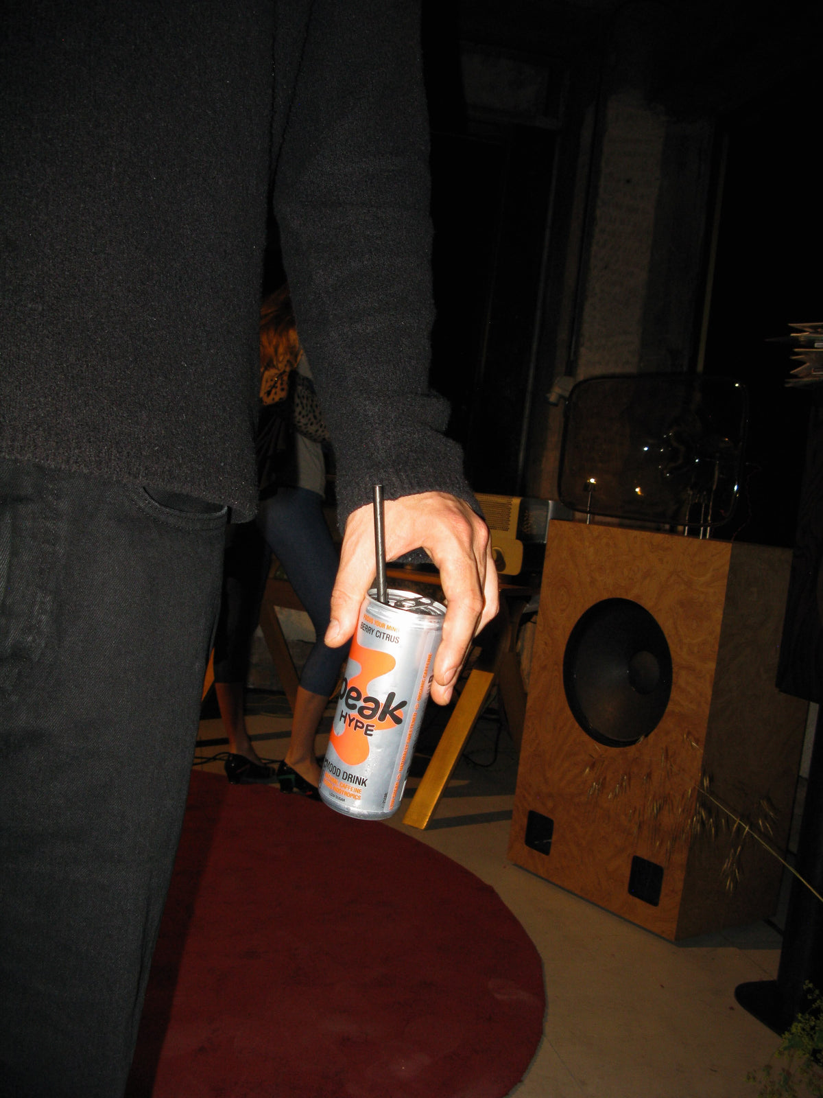A person holding a can of Peak Hype, a drink with natural caffeine from guayusa, next to a wooden speaker