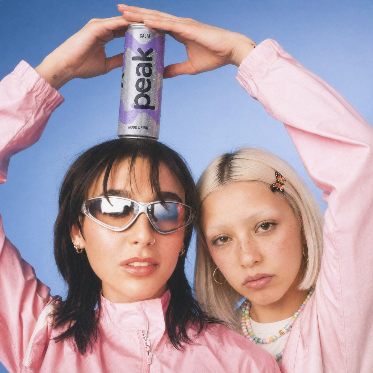 Two friends with a can of Peak Calm balanced on their heads